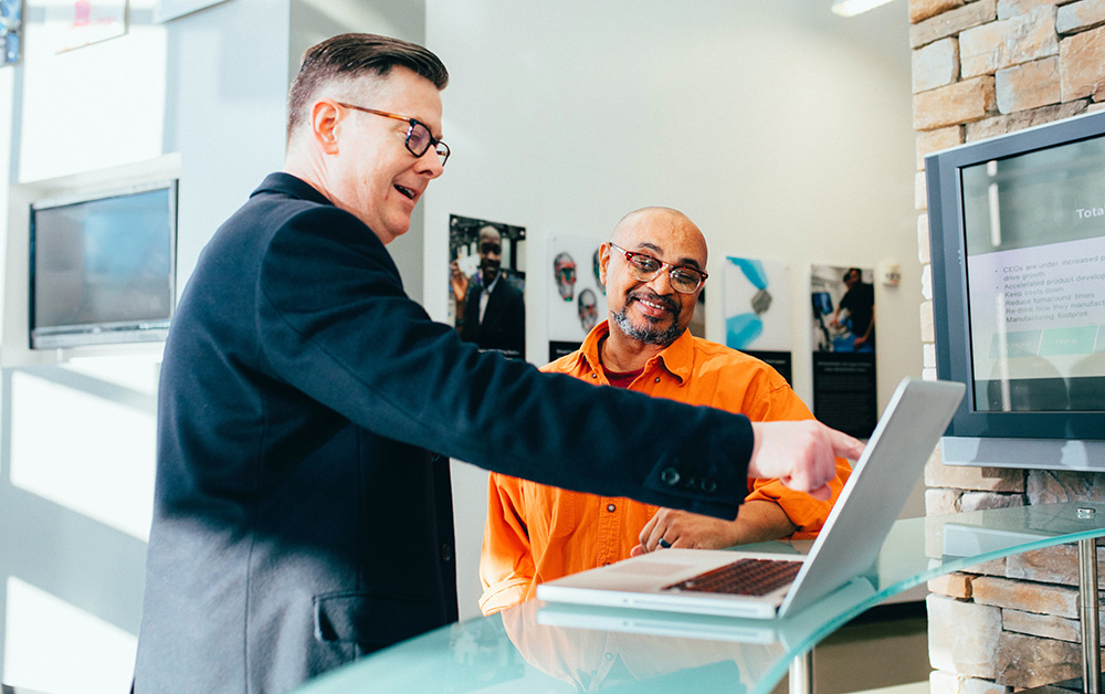 Two coworkers chat over a laptop