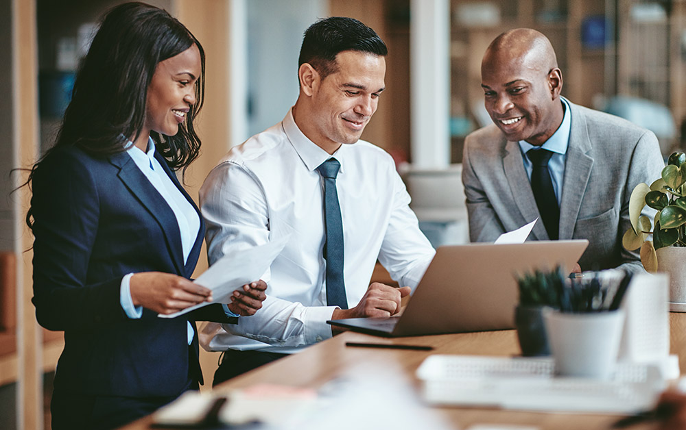 Coworkers gather around a laptop