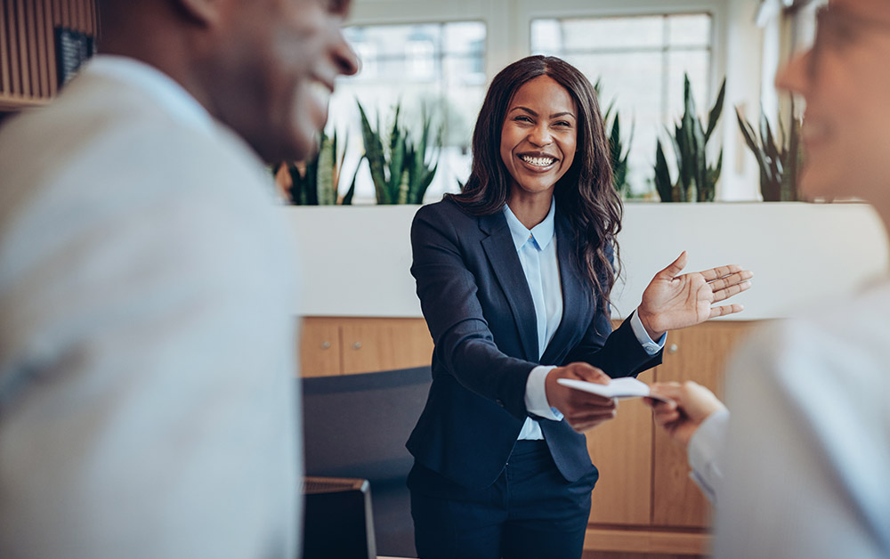 A woman in a meeting hands paper to another women