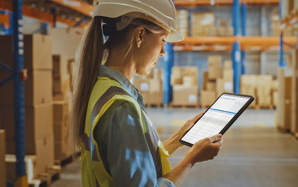 A woman views her tablet in a warehouse